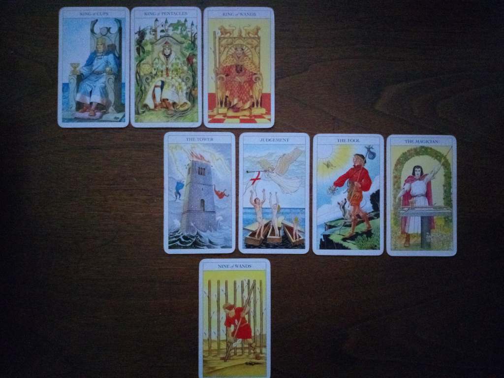 Tarot cards laid out on a table: King of Cups, King of Wands, King of Pentacles, the Tower, Judgement, the Fool, the Magician, Nine of Wands