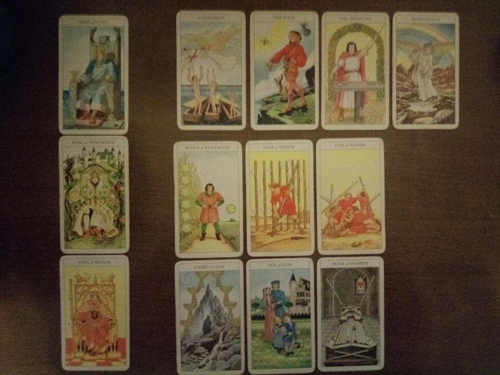 Tarot cards laid out on a table: King of Cups, King of Pentacles, King of Wands, Judgement, the Fool, the Magician, Temperance, Seven of Pentacles, Nine of Wands, Five of Wands, Eight of Cups, Ten of Cups, Four of Swords.