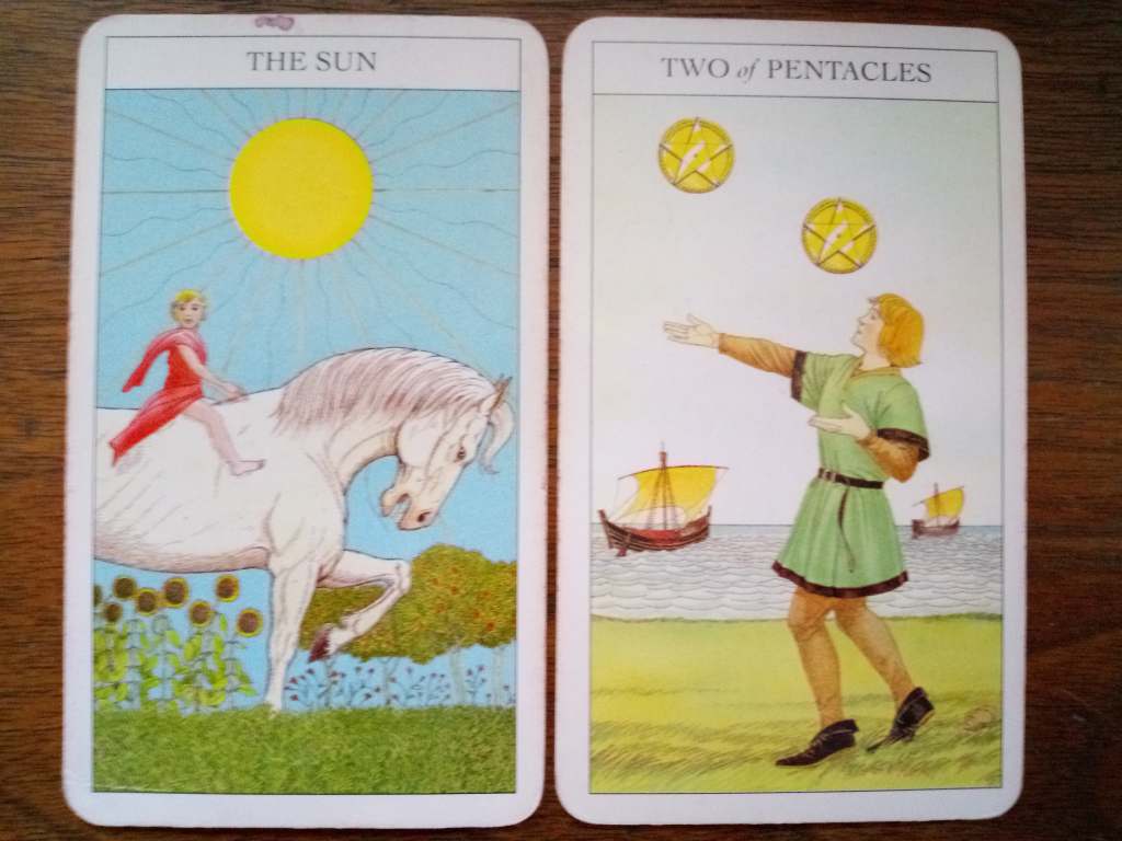 Two tarot cards, the Sun and the Two of Pentacles.