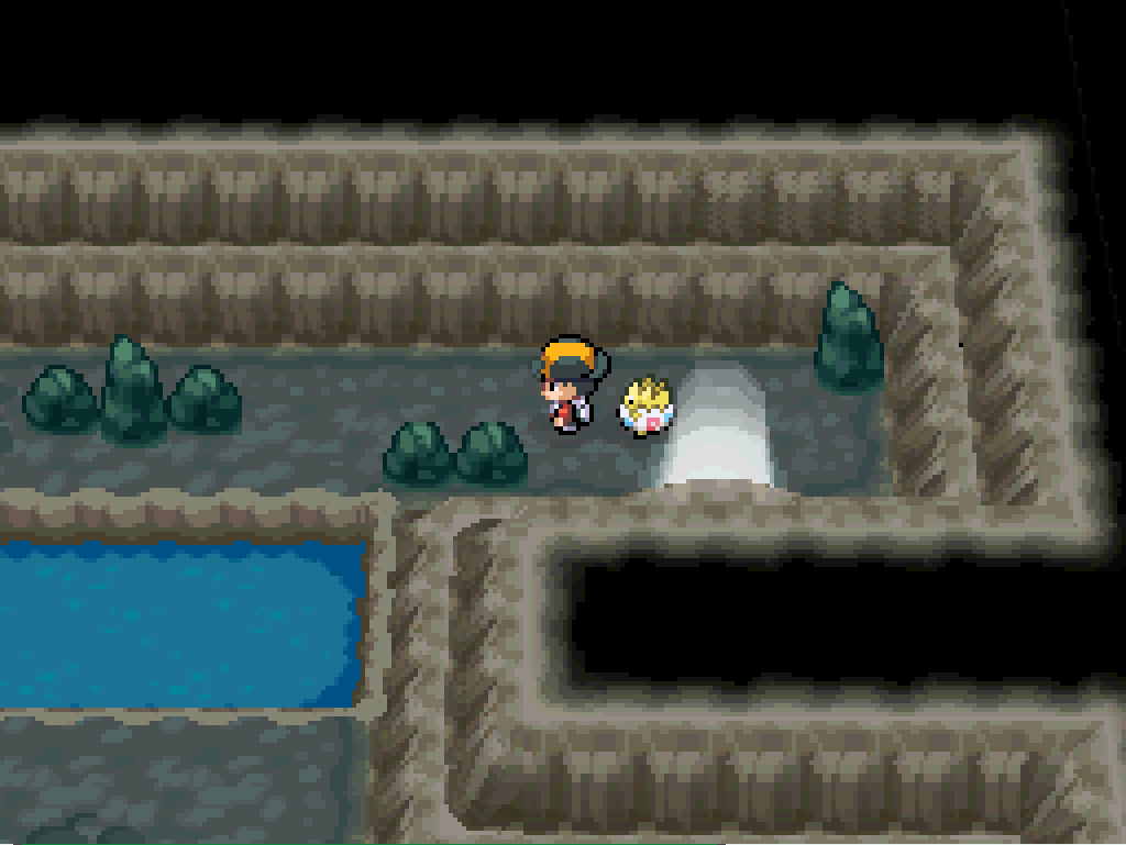 Inside the entrance to Union Cave - stone tunnel walls, scattered boulders,  a pool of water.