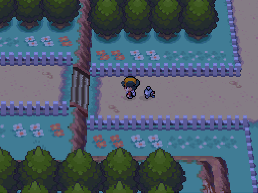 On route 38: a dirt road with white picket fences, flowers and trees on either side.